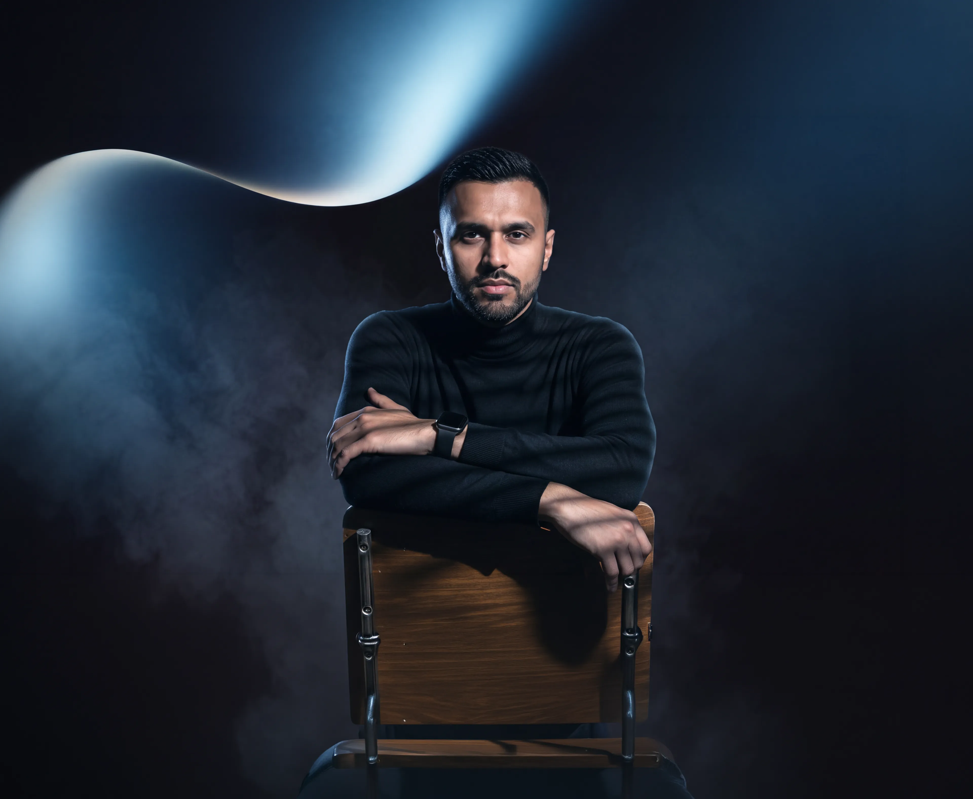 Ajmal Gholzad seated in a dark studio portrait